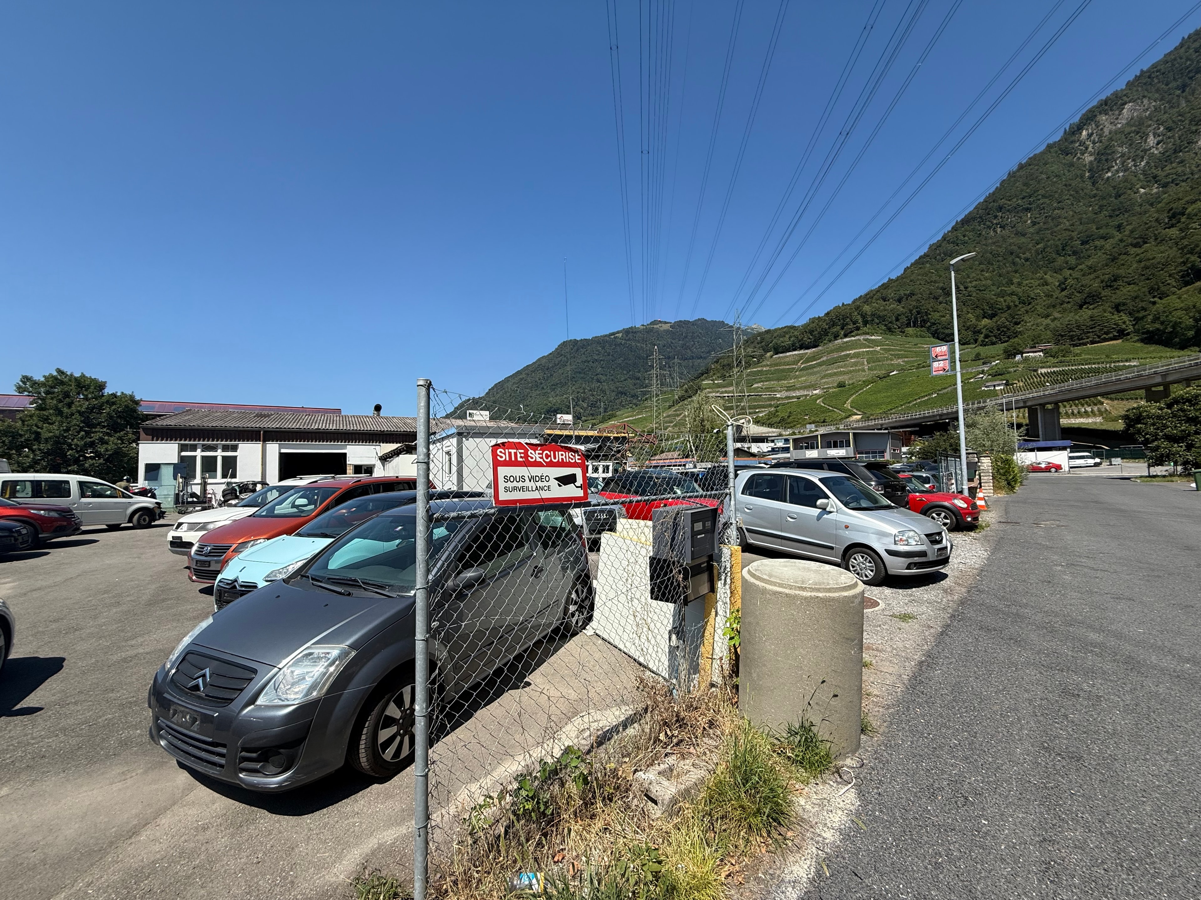 Entrée sécurisée du site AC Automobiles à Villeneuve avec vue sur les Alpes